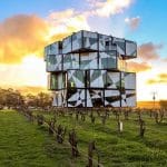 The Cube in McLaren Vale set in the McLaren Vale vineyards with rows of vines , this cube structure is set on a mirror so it looks like it is floating in the air.