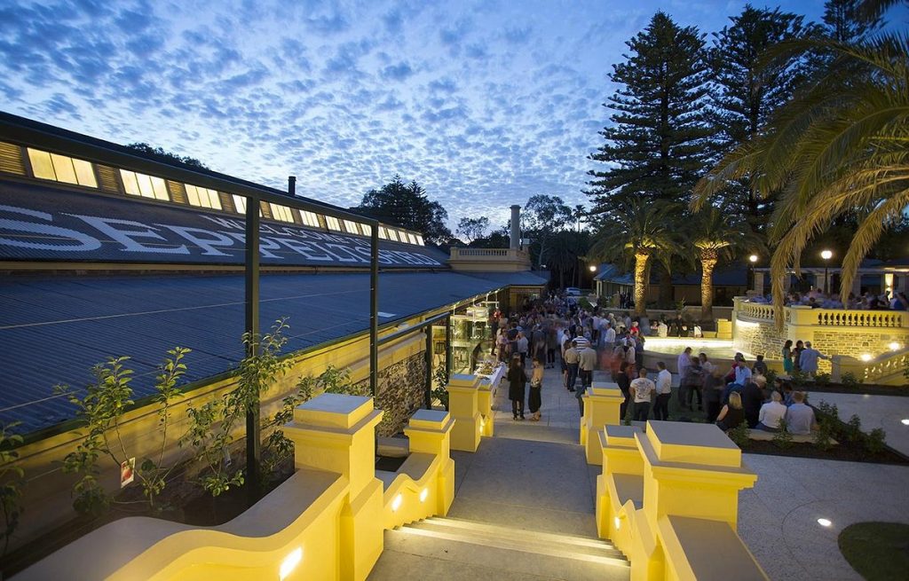 Dusk view of Seppeltsfield Estate courtyard with historic buildings, palm trees and guests